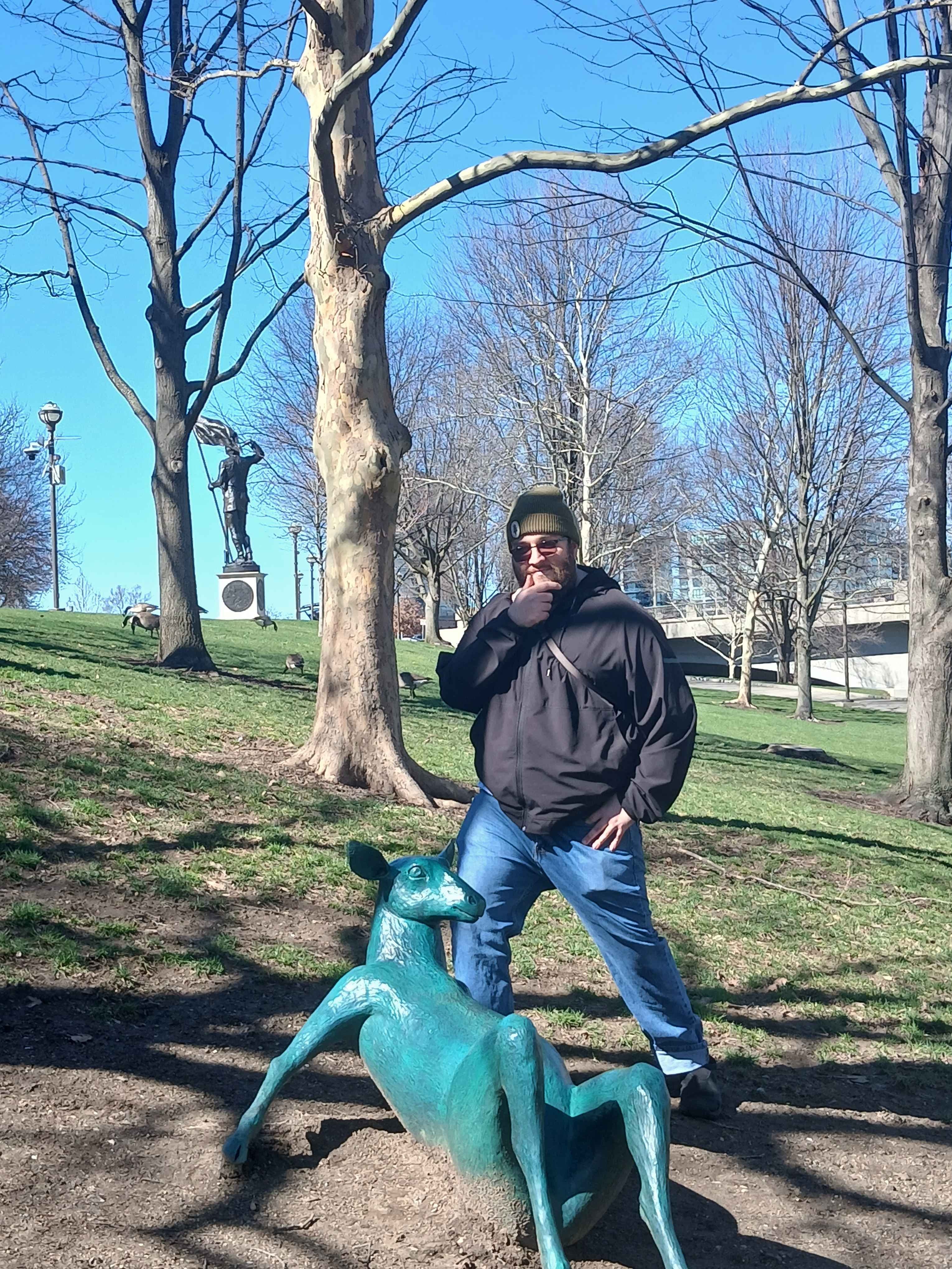 David in a park, posing by a statue